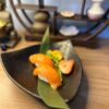 Artfully presented Nigiri Salmon, ready to enjoy, with traditional Japanese shelf in the background.