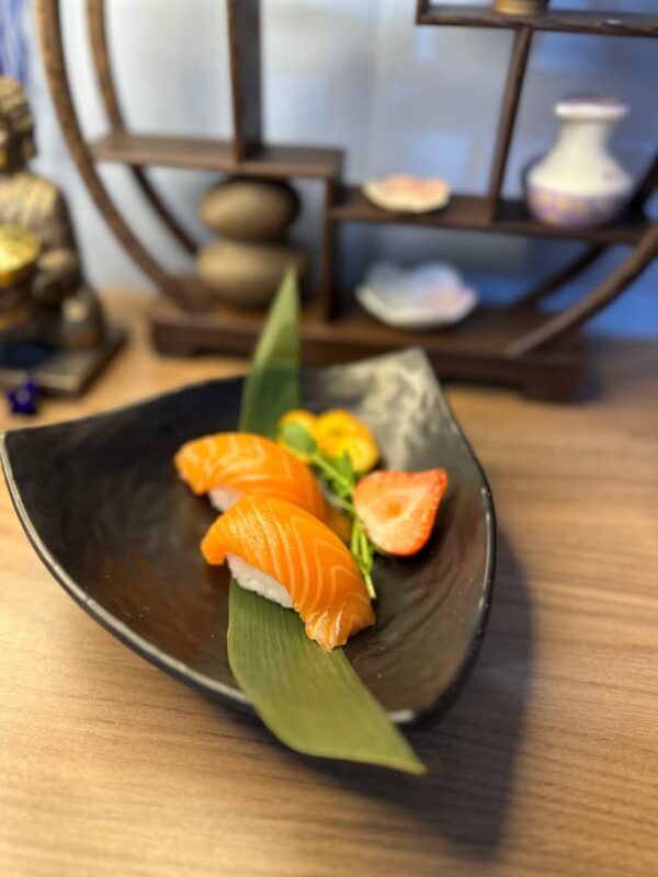 Artfully presented Nigiri Salmon, ready to enjoy, with traditional Japanese shelf in the background.