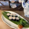 Close-up of Edinburgh Maki Crab rolls on ceramic plate with traditional Japanese ornaments.