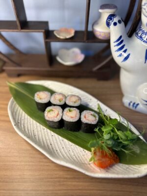 Close-up of Edinburgh Maki Crab rolls on ceramic plate with traditional Japanese ornaments.