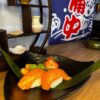 Close-up of Nigiri Salmon with delicate wasabi hint, set against a backdrop of Japanese decor.