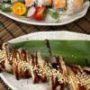 Close-up of a Philadelphia with Eel sushi roll, showcasing the eel's rich texture and sesame seed topping, served in Edinburgh