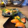 Elegant Nigiri Salmon offering, perfect for a sophisticated snack, presented on a leaf-lined black plate.