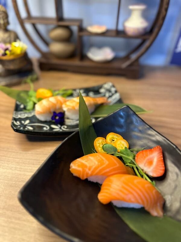 Elegant Nigiri Salmon offering, perfect for a sophisticated snack, presented on a leaf-lined black plate.