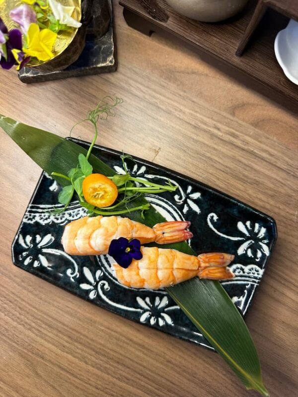 Exquisite Nigiri Shrimp on a leaf, with vibrant garnish, a delicious sushi treat in Edinburgh.