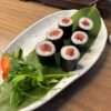 Fresh Maki Salmon sushi snack from Edinburgh, served on a leaf on a white plate with nori wrap.