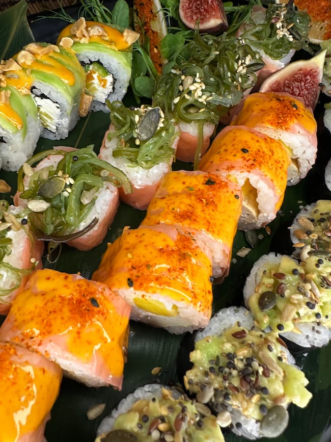 Artful presentation of vegan sushi rolls, including a vibrant salmon-colored avocado-topped roll and seaweed garnished options, reflecting Minami Sushi Edinburgh's commitment to flavor and aesthetics.