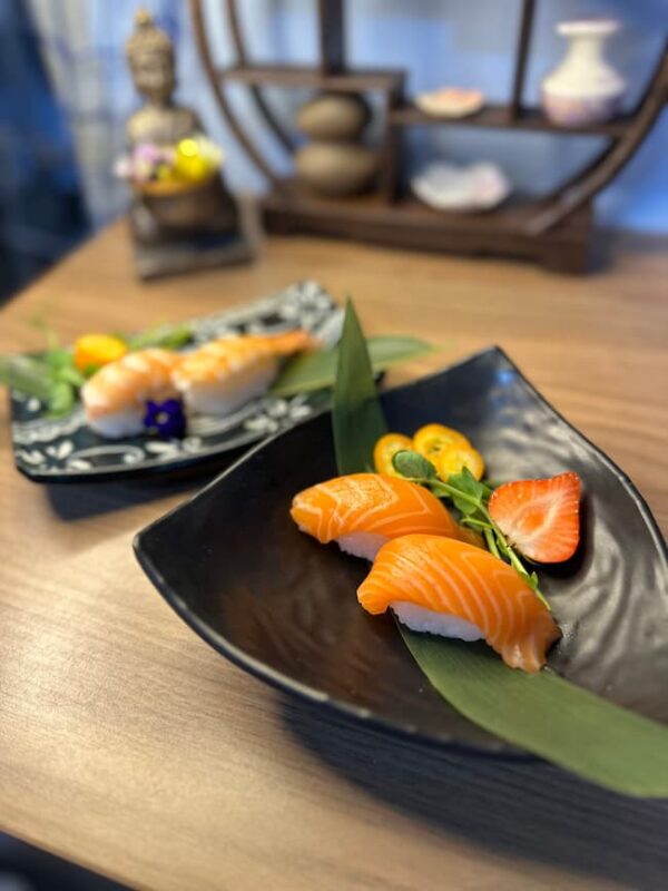 Indulge in luxurious Nigiri Salmon, beautifully served with a touch of nature on a sleek plate.