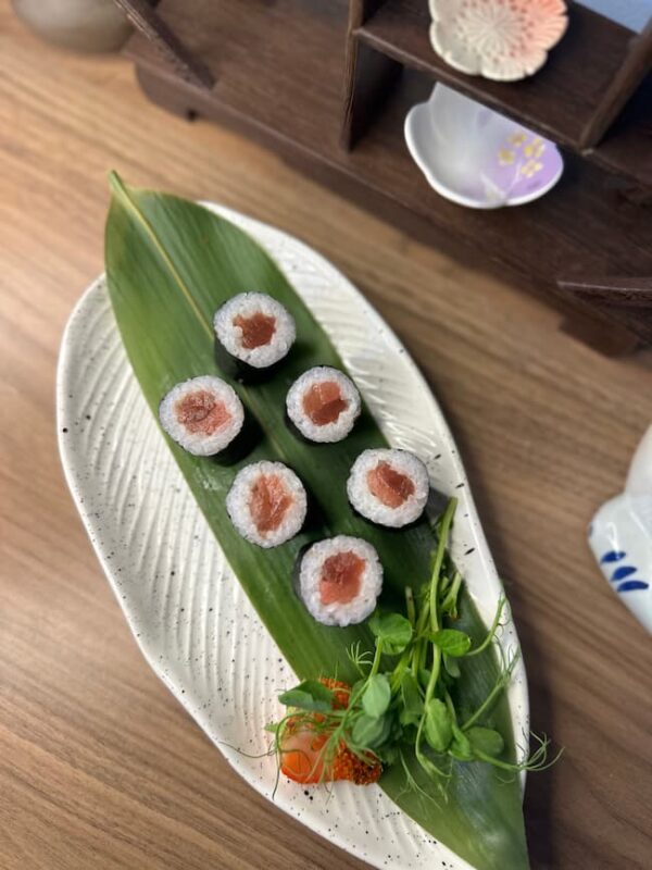 Maki Salmon sushi rolls on a white plate with a green leaf, perfect snack in Edinburgh.