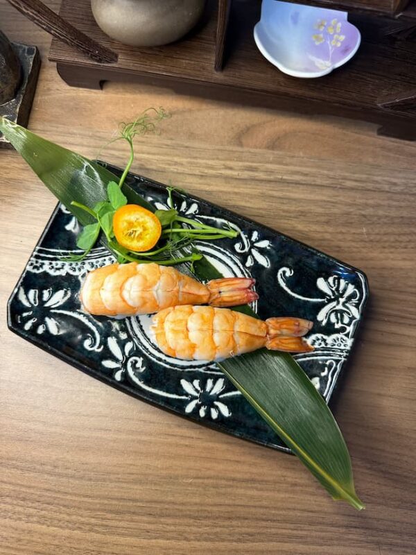 Nigiri sushi featuring plump shrimp, a classic Edinburgh snack, presented with delicate garnishes.