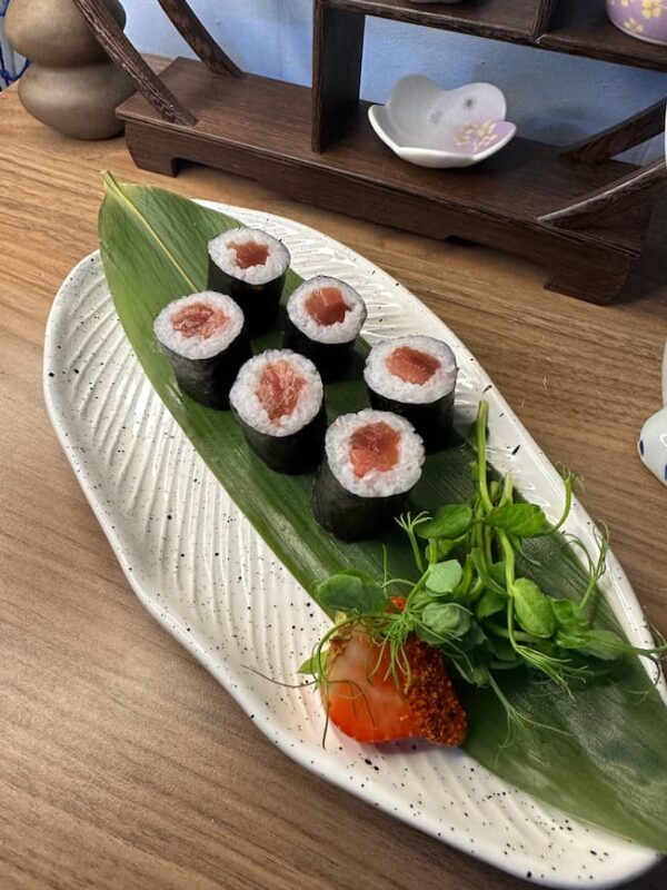 Overhead view of Maki Salmon rolls, a classic Edinburgh sushi snack on a textured plate.