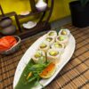 Salmon Avocado Roll sushi arranged on a ceramic plate over a bamboo mat, showcasing fresh avocado and sesame seeds, in Edinburgh sushi restaurant