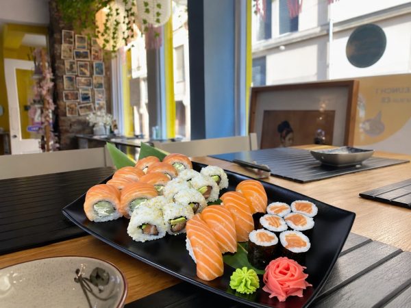 A black plate with Salmon Lover Sushi set on a wooden table in a brightly lit restaurant.