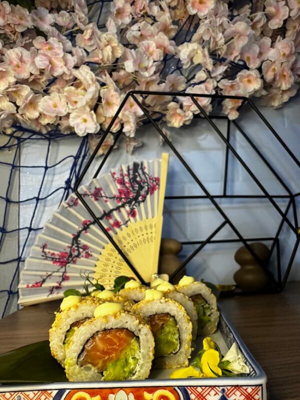 California Classic Sesame rolls topped with sauce on a decorative tray, set against a backdrop of cherry blossoms and geometric ornaments, evoke the elegance of Edinburgh's unique charm.