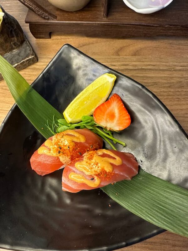 Savory tuna nigiri paired with fresh strawberry and lemon, a delightful bite in Edinburgh