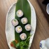 Top view of Maki Crab sushi in Edinburgh with garnish on a white plate and wooden shelf backdrop.