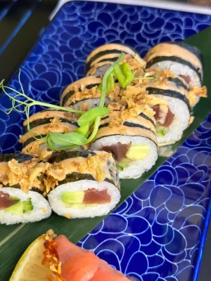 Elegant Futomaki tuna sushi arrangement on a leaf over a blue wave-patterned plate, perfect for a gourmet experience in Edinburgh