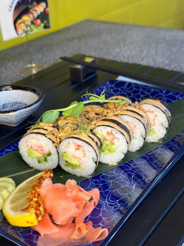 Elegant display of Futomaki crab sushi on a leaf with lemon and spicy toppings, enhancing the dining experience in Edinburgh