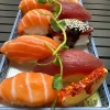 Full view of assorted nigiri sushi set, artistically arranged on a blue plate against an Edinburgh street backdrop