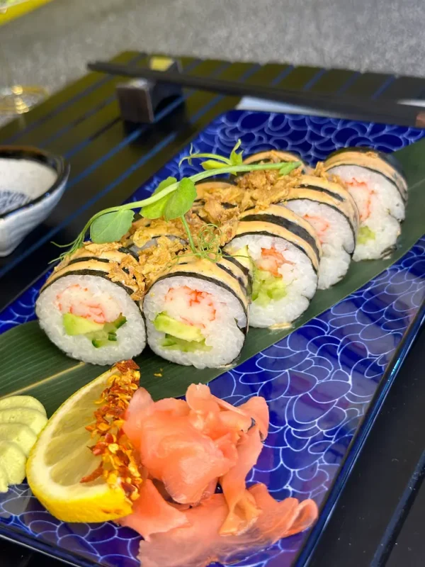 Futomaki crab sushi rolls adorned with green pepper and crispy onions on a blue patterned plate, perfect for sushi lovers in Edinburgh