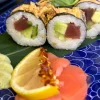 Futomaki tuna rolls garnished with green pepper and crispy onions, served on a blue patterned plate in Edinburgh