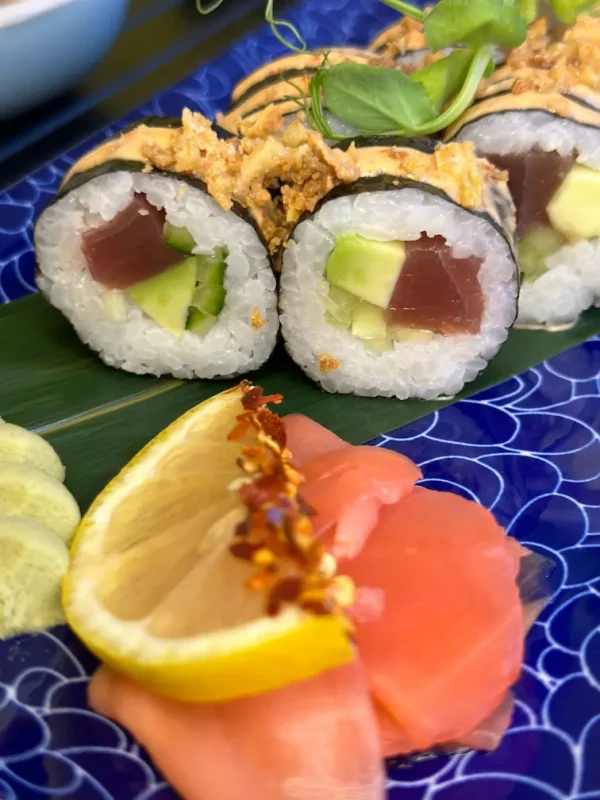 Futomaki tuna rolls garnished with green pepper and crispy onions, served on a blue patterned plate in Edinburgh