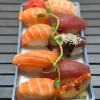 Vertical view of assorted nigiri sushi including salmon and tuna, served on a stylish blue plate in Edinburgh