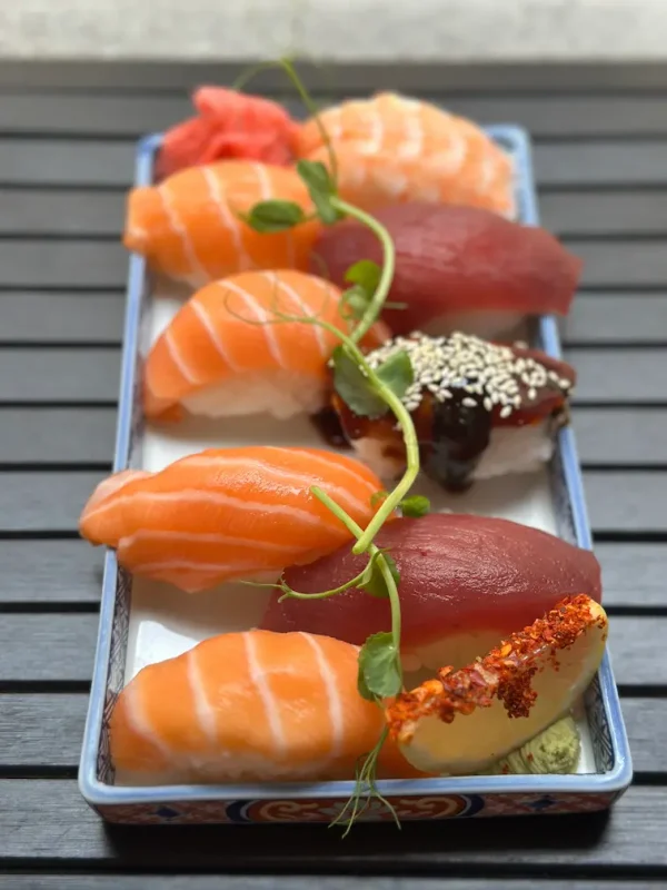 Vertical view of assorted nigiri sushi including salmon and tuna, served on a stylish blue plate in Edinburgh