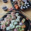 The Imperial feast set features two trays of assorted sushi rolls, sashimi, wasabi, ginger, soy sauce, and chopsticks on a wooden table.