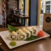 California shrimp (rice, nori, cucumber, avocado, shrimp, sesame, mayo) A plate of California shrimp sushi rolls topped with tobiko, wasabi, and pickled ginger sits beside a Minami menu on the table.