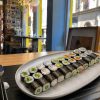 A Maki set is served on a wooden table in a bright restaurant with yellow walls.