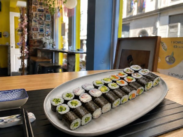 A Maki set is served on a wooden table in a bright restaurant with yellow walls.