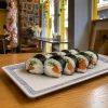 A rectangular plate with eight Futomaki Salmon Phila sushi rolls on a wooden table in a restaurant.
